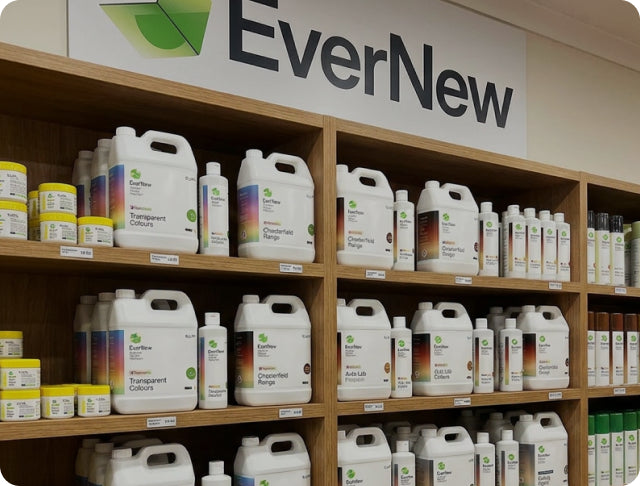 Wooden display shelves stocked with EverNew brand leather pigment containers, including large white jugs and smaller bottles, under a large EverNew sign.
